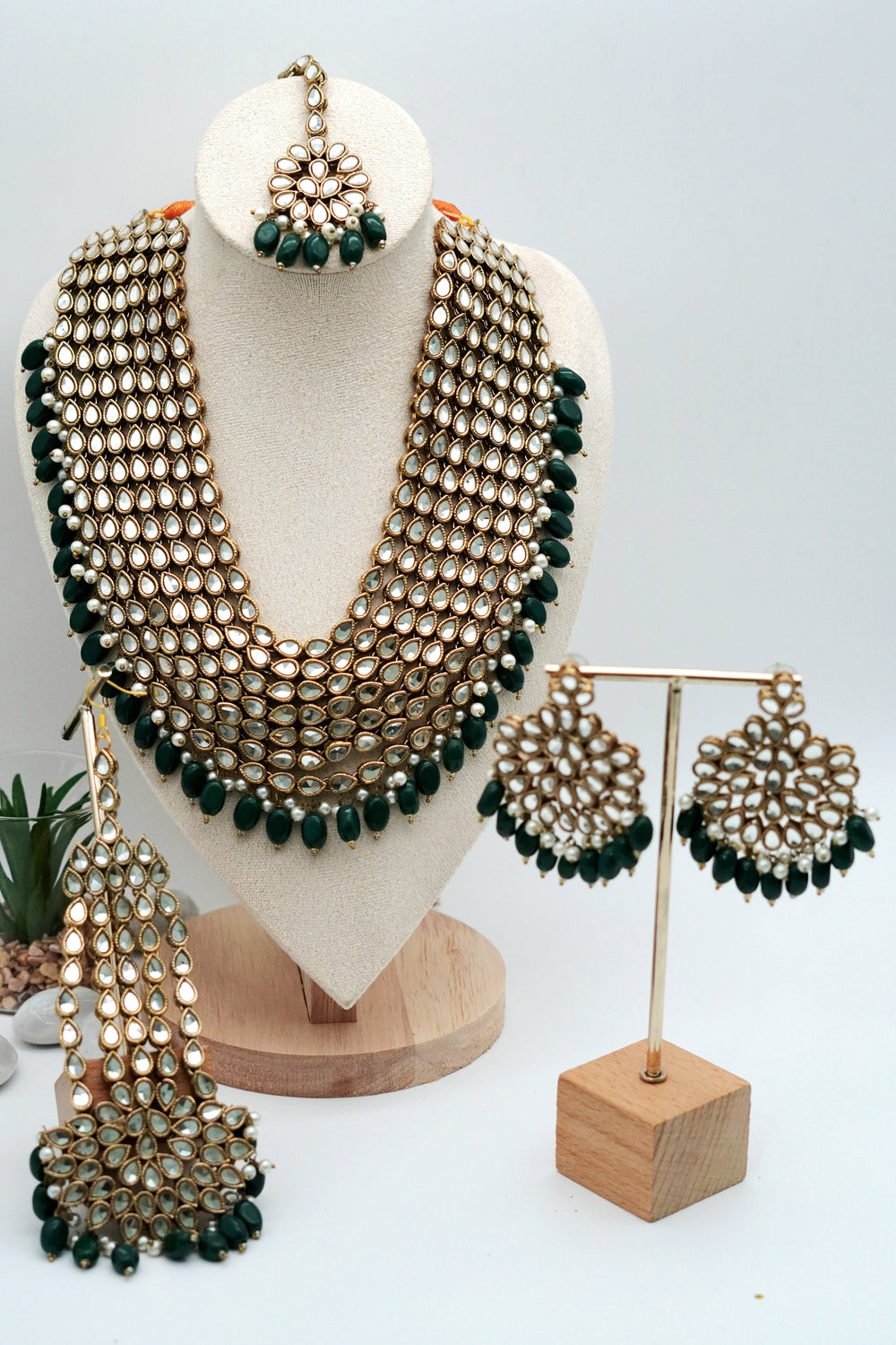 Jewelry set including necklace, earrings, and maang tikka on a mannequin and stand.