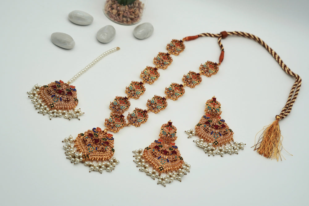 Ornate jewelry set with necklace, earrings, and bracelet on a light background
