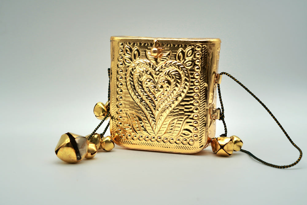 Gold decorative item with heart design and bells on a gray background