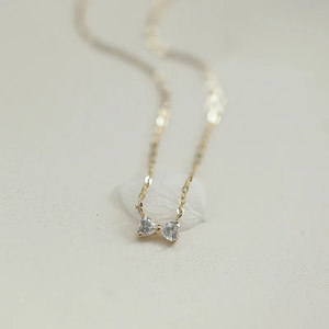 Gold necklace with heart-shaped pendants on a light gray background