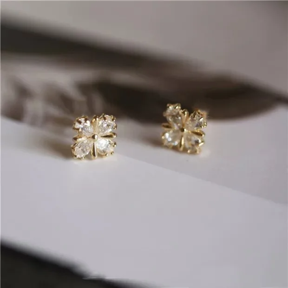 Gold earrings with clear gemstones on a light background
