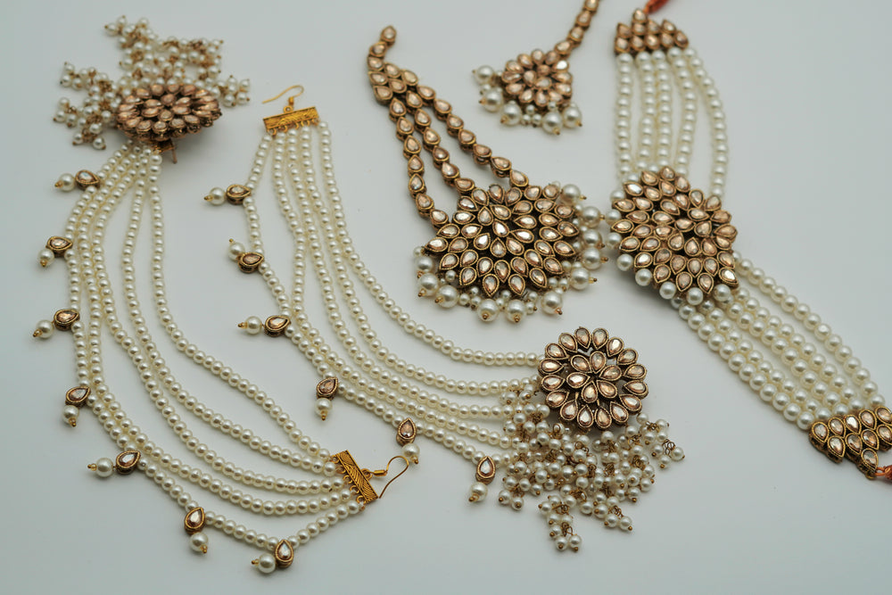 Gold and pearl jewelry set on a light gray background
