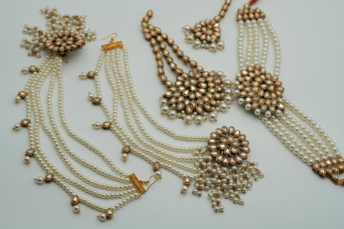 Gold and pearl jewelry set on a light gray background