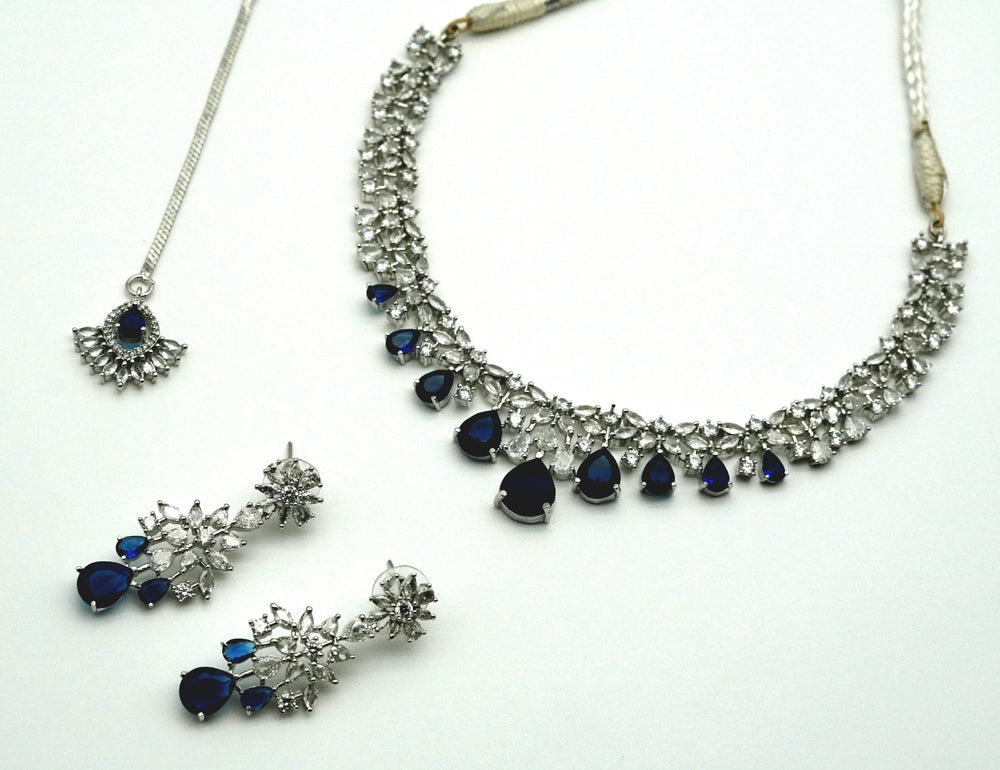 Jewelry set with necklace and earrings featuring blue stones on a white background