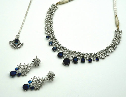 Jewelry set with necklace and earrings featuring blue stones on a white background